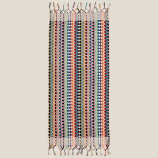 Colourful polka dot towel with tassels on a beige background.