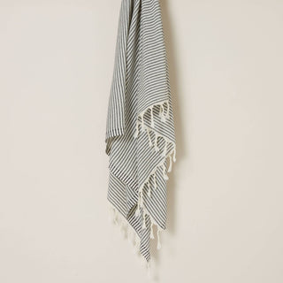 Black and white striped towel with white tassels on a beige background.