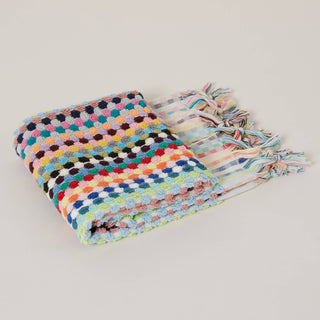 Multicoloured pom-pom patterned towel with tassels on a beige background.