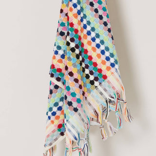 Colourful pom-pom patterned towel with tassels on a plain background.