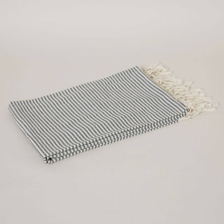 Black and white striped towel with white tassels on a beige background.