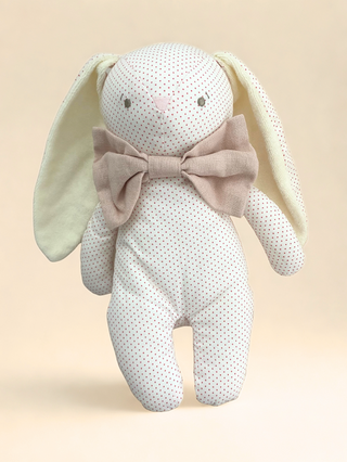 Stuffed bunny toy with a bow on a beige background.