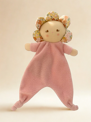 Doll with floral headband and pink fleece body, pictured on a beige background.