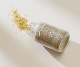 Bare Mum sitz bath salts spilling out of a jar on a light background.