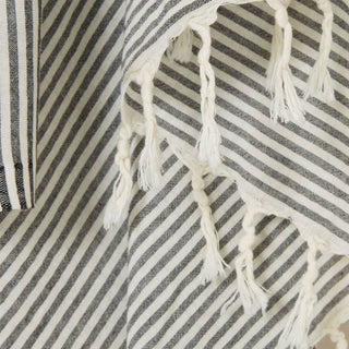 Close up visual of striped black and white towel with white tassels.
